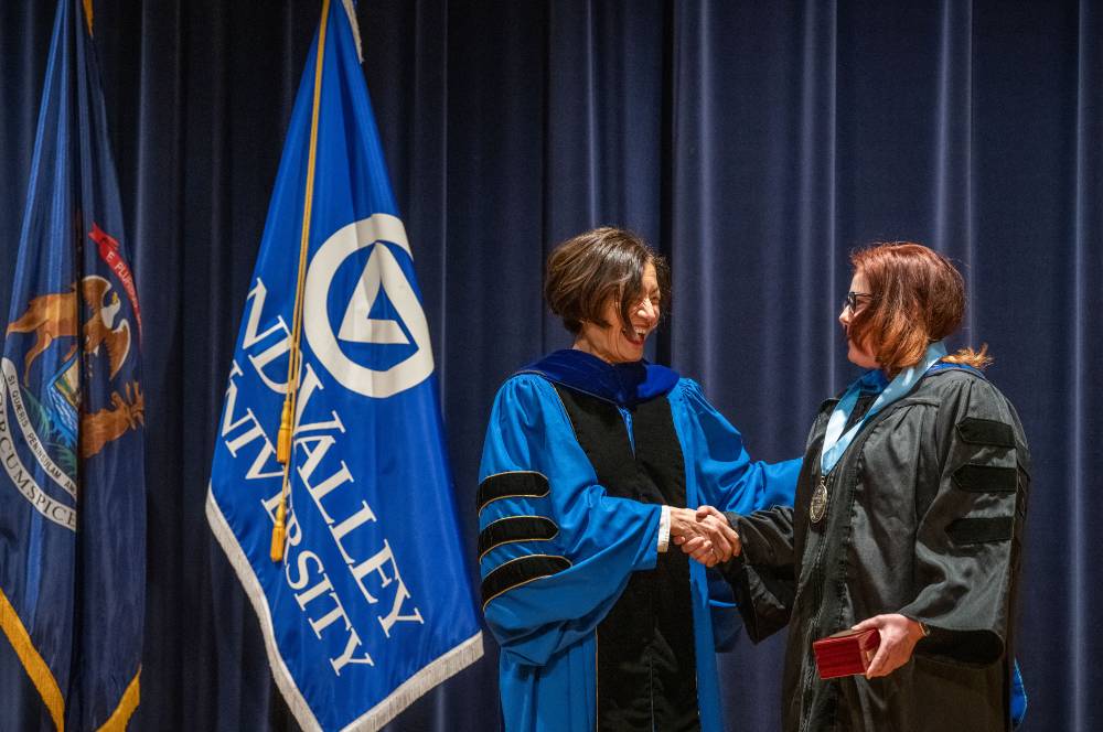 Provost Mili smiles and shakes hands with woman